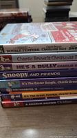 Stack of 8 DVDs including Peanuts titles showing spine titles clearly for identification