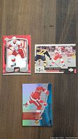 Three Steve Yzerman hockey cards laid out on wooden surface. Cards show various images and designs with red, white, and blue/holographic elements.