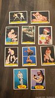 Top-down view of all 10 wrestling cards arranged on a table, showing full fronts and card details clearly
