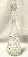 Full view of the tall etched cut crystal decanter with ornate stopper on top