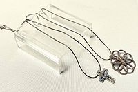 Two 17 inch sterling silver chains displayed on transparent stands, showing the cross pendant and geometric pendant