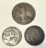 Three coins arranged on light fabric showing front faces of one penny and two half pennies