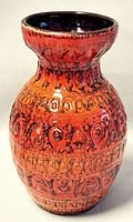 Front side view of the burnt orange glazed vintage pottery vase with textured circular and teardrop shape patterns.