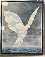 Full view of large framed René Magritte 'La Grande Famille' poster showing the bird silhouette with sky/clouds pattern and ocean scene below.