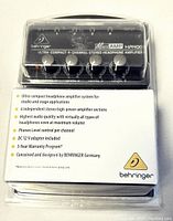 Front view of the Behringer MicroAmp HA400 amplifier in sealed blister packaging showing four volume knobs and power switch.