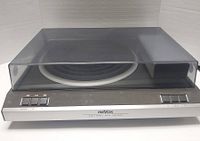 Front view of turntable with dust cover closed showing power and speed control buttons