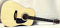 Full length photo of Squier SA-150 acoustic guitar showing natural wood grain top and black pickguard.