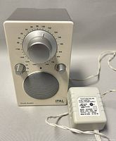 Front view of Tivoli Audio iPAL radio showing tuning dial, AM/FM selector and speaker grille.