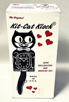 Original retail box for the Kit-Cat Klock showing black cat illustration with red hearts and text about rolling eyes and wagging tail.