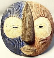 Front view of vintage Akan Anoma African bird wall mask painted with blue and terracotta colors showing carved texture and central nose.