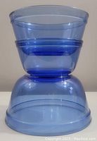 Three cobalt blue glass mixing bowls stacked together showing varying sizes and translucent blue color.
