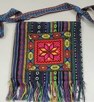 Front view showing the colorful needlecraft patch, vertical stripes, and fringe along bottom edge, with patterned shoulder strap spread out.