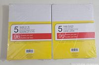 Two packages of notepad pads side by side, one containing 5 Quad 4:1 inch notepads and the other 5 Wide Ruled notepads, both wrapped in clear plastic with yellow and white label.