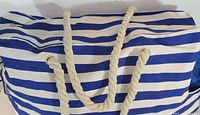 Close-up of blue and white striped beach bag with cotton rope handles on top.