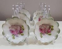 Set of 6 RS Germany porcelain floral napkin holders displayed in two rows on clear stands showing scalloped edges and floral designs.