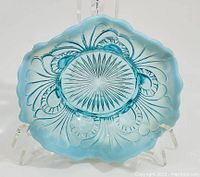 Top view of blue glass footed dish with starburst and loop pattern etched into base, showing scalloped edge and opalescent finish.