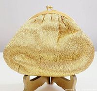Front angle of the vintage Du-Val golden evening bag displayed on stand, showing full shape and metal frame clasp.