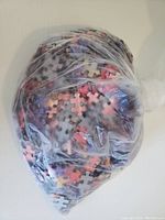 Plastic bag filled with loose puzzle pieces, multicolored with shades relevant to cityscape puzzle colors.