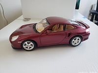 Side profile of the metallic dark red Burago 1:18 Porsche Turbo 996 model showing intact body and windows.