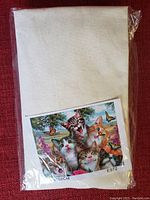 Sealed plastic package containing the needlepoint fabric with a printed template pattern of six playful kittens with butterflies and flowers.