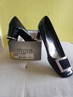 Pair of black patent leather Franco Sarto shoes with box, showing overall side profile and heel detail with metallic accent.