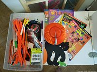 Overview photo of Halloween-themed craft supplies, Highlights booklets, pipe cleaners, false nails, and stickers organized in plastic container