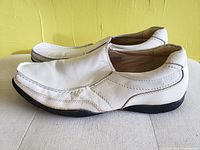Side view of men's white leather deck shoes, showing wear and condition.