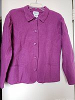 Front view of fuchsia pink women's sweater with buttons and pockets, showing texture and collar.