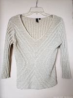 Front view of grey knit sweater showing the unique weave pattern, V-neck, and 3/4 sleeves.