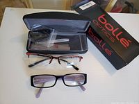 Two pairs of reading glasses displayed with Bolle Optics box and case, showing both glasses fully visible