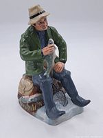 Front angle showing fisherman holding fish, detailed facial features, and naturalistic base with additional fish.