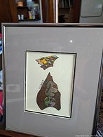 Full view of the framed abstract art showing the composition of multiple stylized faces and eyes, signed "147 Duckitt".