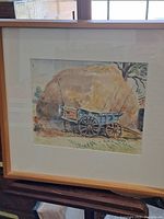 Full view of framed watercolour of hay wagon and haystack, showing the light wood frame and white matting.