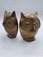 Pair of brass owl bookends shown from front and side with detailed large circular eyes.