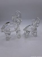 Two clear glass elephant figurines on flat surface, showing size difference and overall shape.