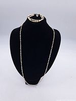 Pearl necklace displayed on black bust stand showing length and clasp.