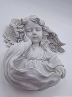 Front view of plaster angel girl wall hanging showing full figure, smiling face, flowing robe and textured feather wings