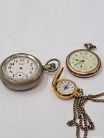 All three pocket watches shown on white background, varying in metal tone and style, seen from top and side angles.
