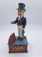 Front view of the vintage cast iron Uncle Sam coin bank showing figure and rectangular base with eagle design and lettering.