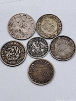 Photo showing six world silver coins from Hong Kong, Straits Settlements, and Australia including various denominations and visible wear.