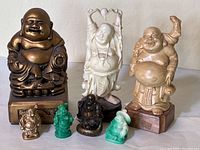 Front view of the 7 Buddha figurines in various sizes and materials showing their relative heights and details