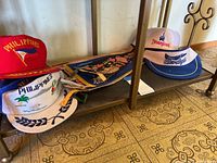 Photo showing five hats and seven pennants on shelving unit with floor patterned tiles.
