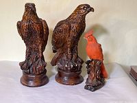 Full view of two brown falcon figurines and one red cardinal figurine showing overall size and condition.