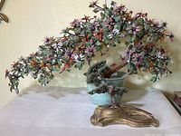 Wider view showing the large faux bonsai tree with multicolored flowers and the smaller bonsai tree set in decorative pots.