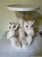Front view of the small occasional table showing the detailed sculpted owls on the base and the circular top surface.