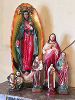 Wide view showing all six figurines arranged together with Virgin Mary figure in colorful frame as the tallest.