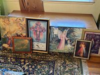 All 6 religious wall art pieces arranged on floor showing variety in size and frame styles, includes clock