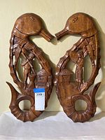 Front view of the matched pair of carved wooden seahorses with attached carved figures and huts.