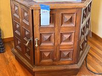 Hexagonal wood end table showing detailed wood paneling on the two doors of the storage compartment.