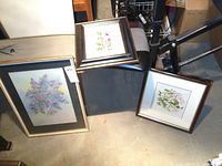 Three framed artworks including a large 11x17 floral watercolour, a smaller 5x7 floral watercolour by Plato, and an 8x8 framed stitched fabric art piece.